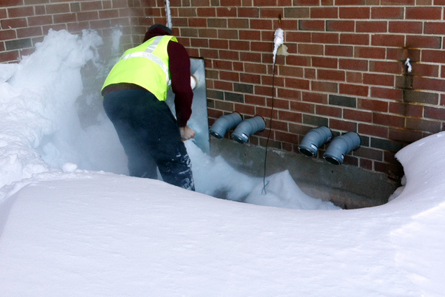 Dan LaBonte, area coordinator for Residential Life, shovels out heating vents at Park Washington Apartments.